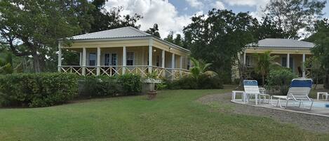 A two-story yellow building with a covered porch and a pool area with lounge chairs.