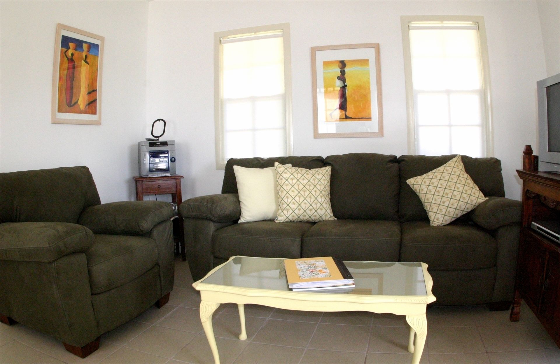A living room with a sofa set, a glass coffee table, and a television.