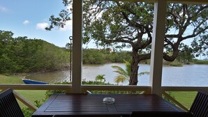 A wooden table and chairs on a deck with a view of a lake and trees. - Yepton Estate Cottages (St. John's)