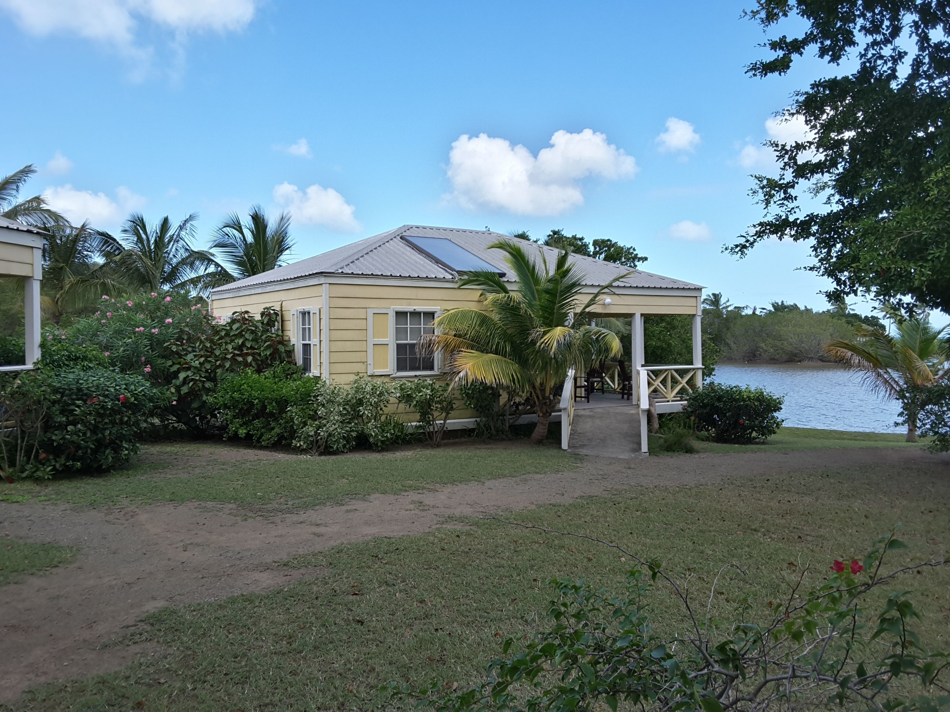 A yellow house with a covered porch and a view of a lake.