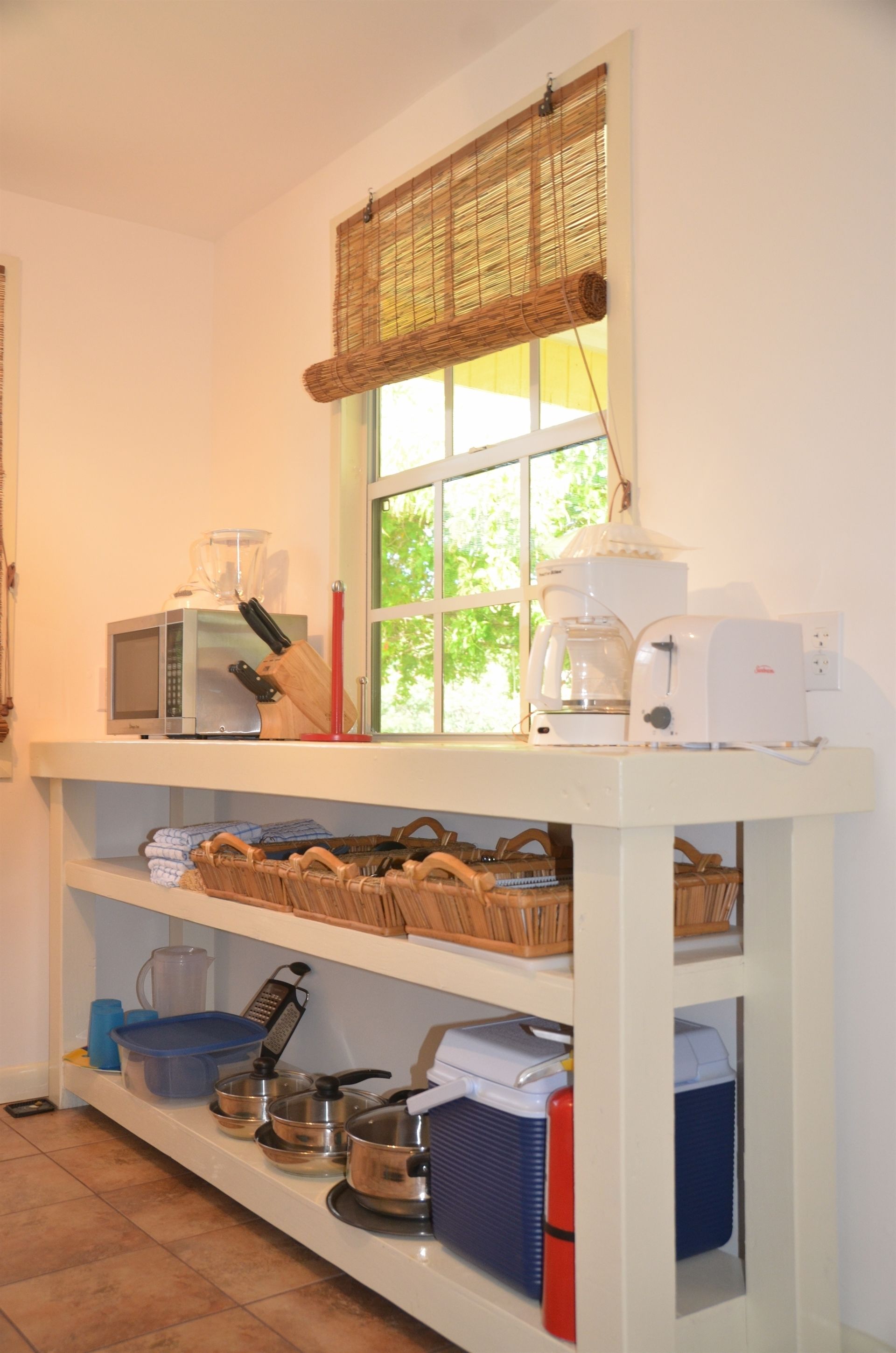 A kitchen with a microwave, coffee maker, and various kitchen utensils on shelves.