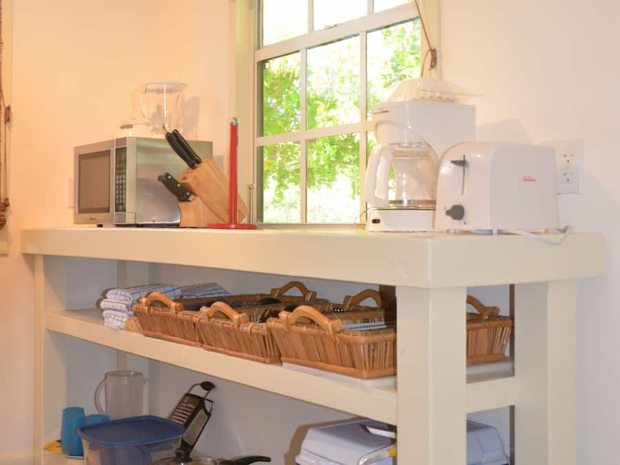 A kitchen with a microwave, coffee maker, and various kitchen utensils on shelves.