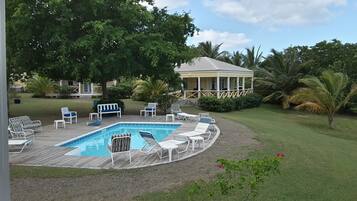 Un área de piscina con sillones de descanso y un pabellón.