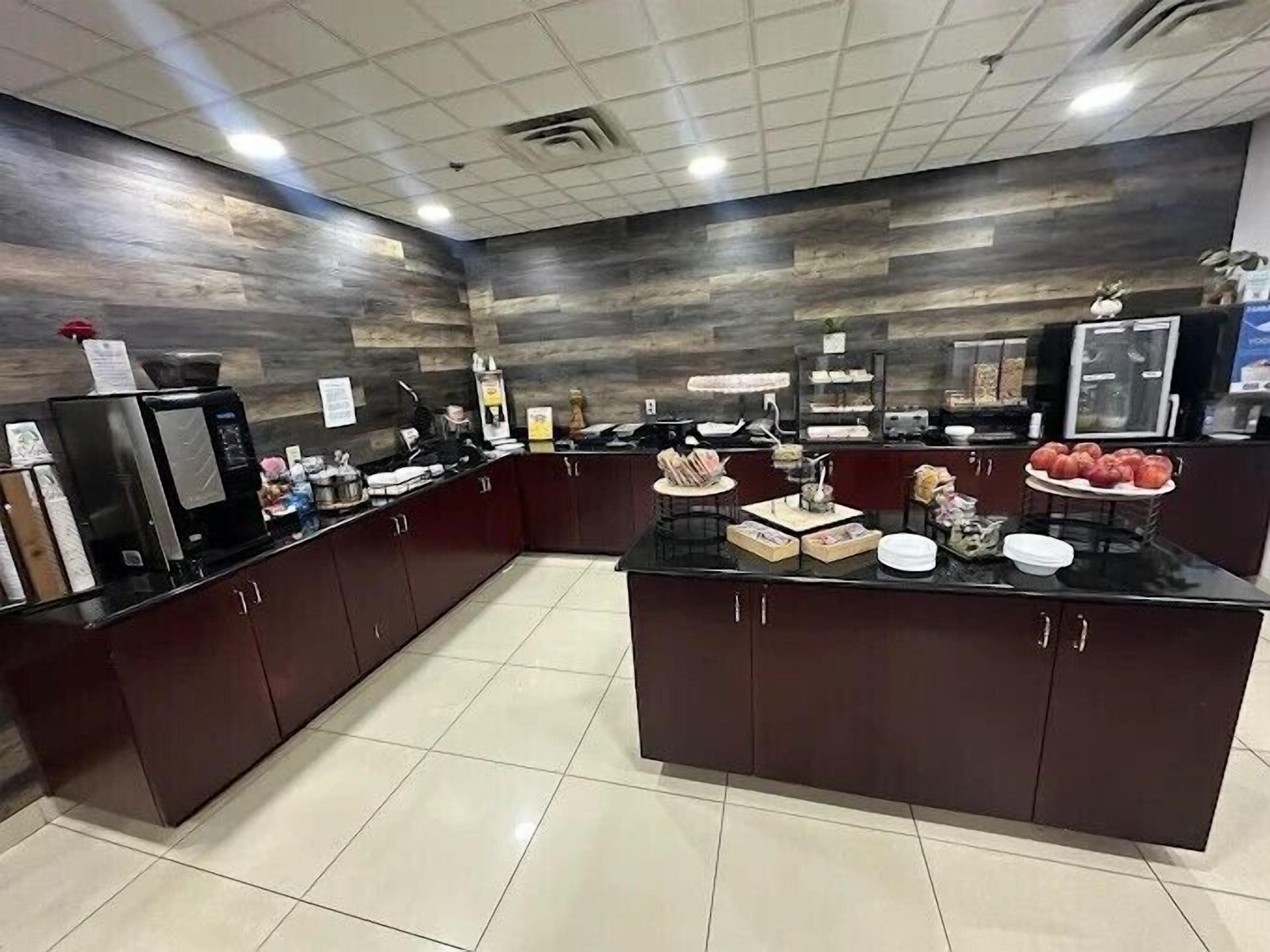 A modern kitchen with dark cabinetry, a central island, and various food items displayed on the counter.