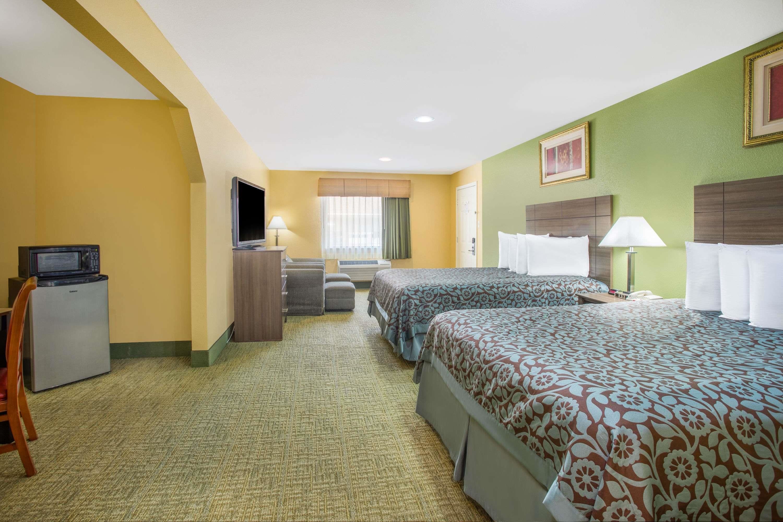 A hotel room with two beds, a desk, a television, and a microwave.