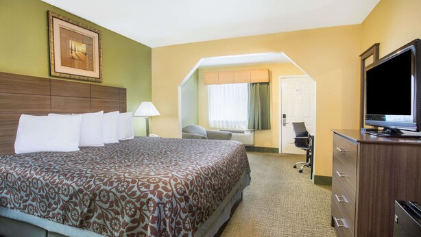 A hotel room with a large bed, a desk with a chair, a television, and a wardrobe. - Days Inn by Wyndham Abbeville (Abbeville)
