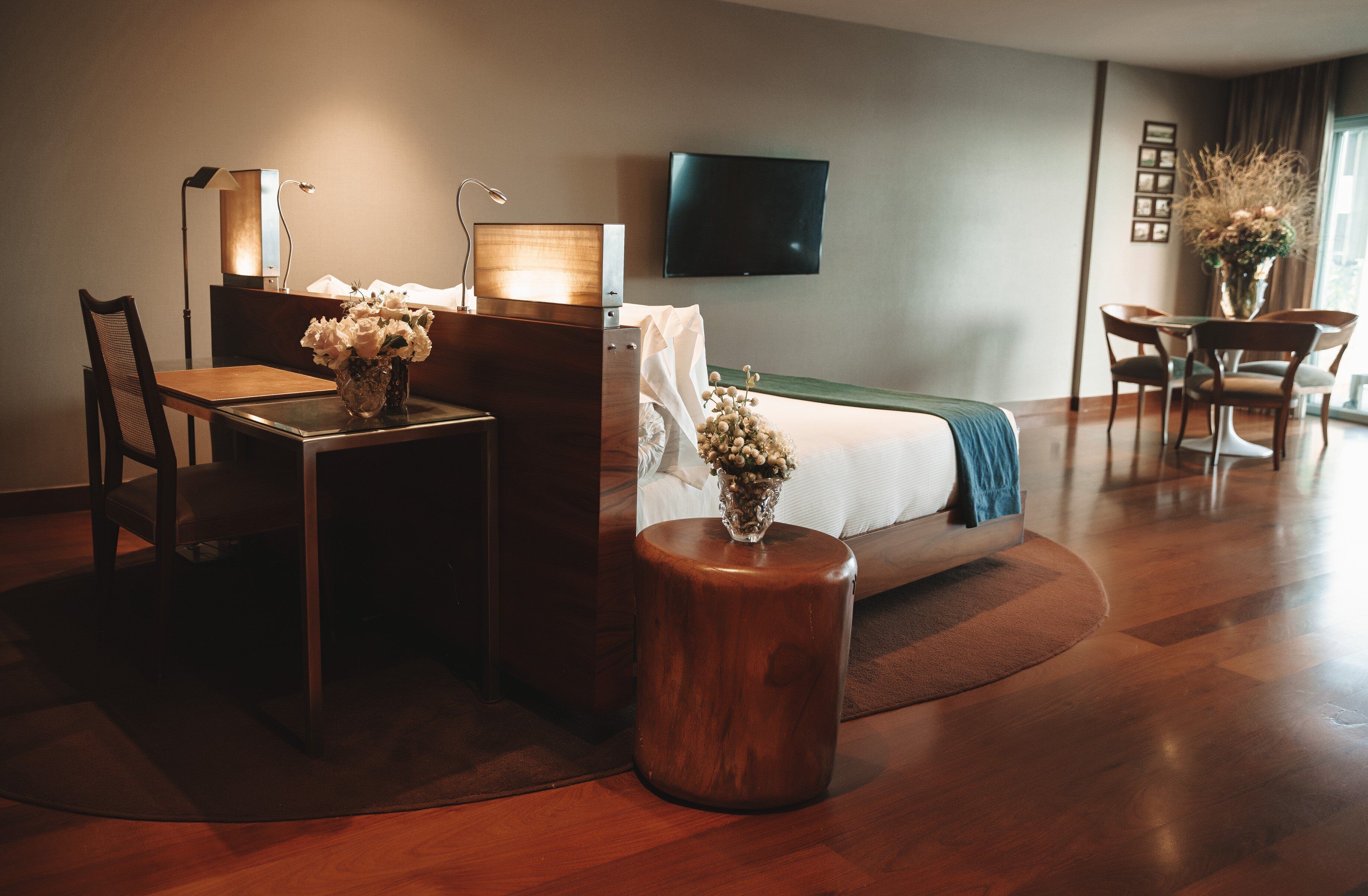 Habitación de hotel con cama, escritorio, silla y televisor montado en la pared.