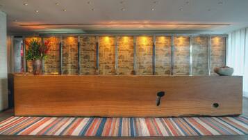 A reception area with a wooden reception desk, a striped rug, and a wall with vertical panels.