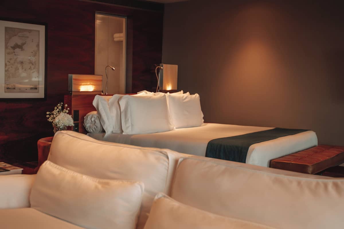 A hotel room with a bed, a nightstand, a lamp, and a framed map on the wall.