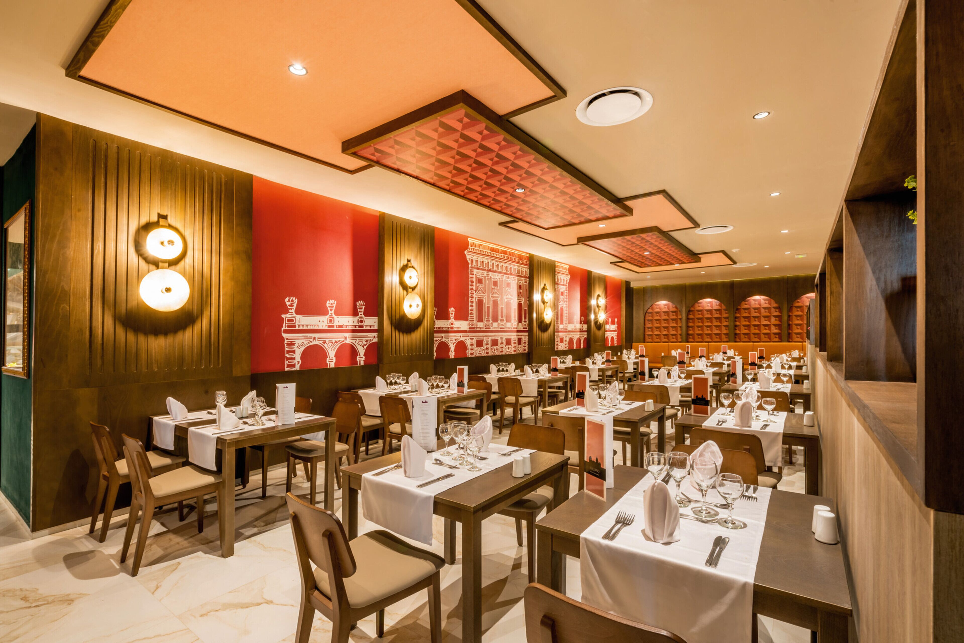 A restaurant with multiple tables set for dining, featuring a modern interior with wooden paneling and red accents.