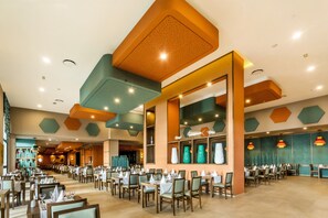 A spacious restaurant with multiple dining areas, high ceilings, and modern lighting fixtures.