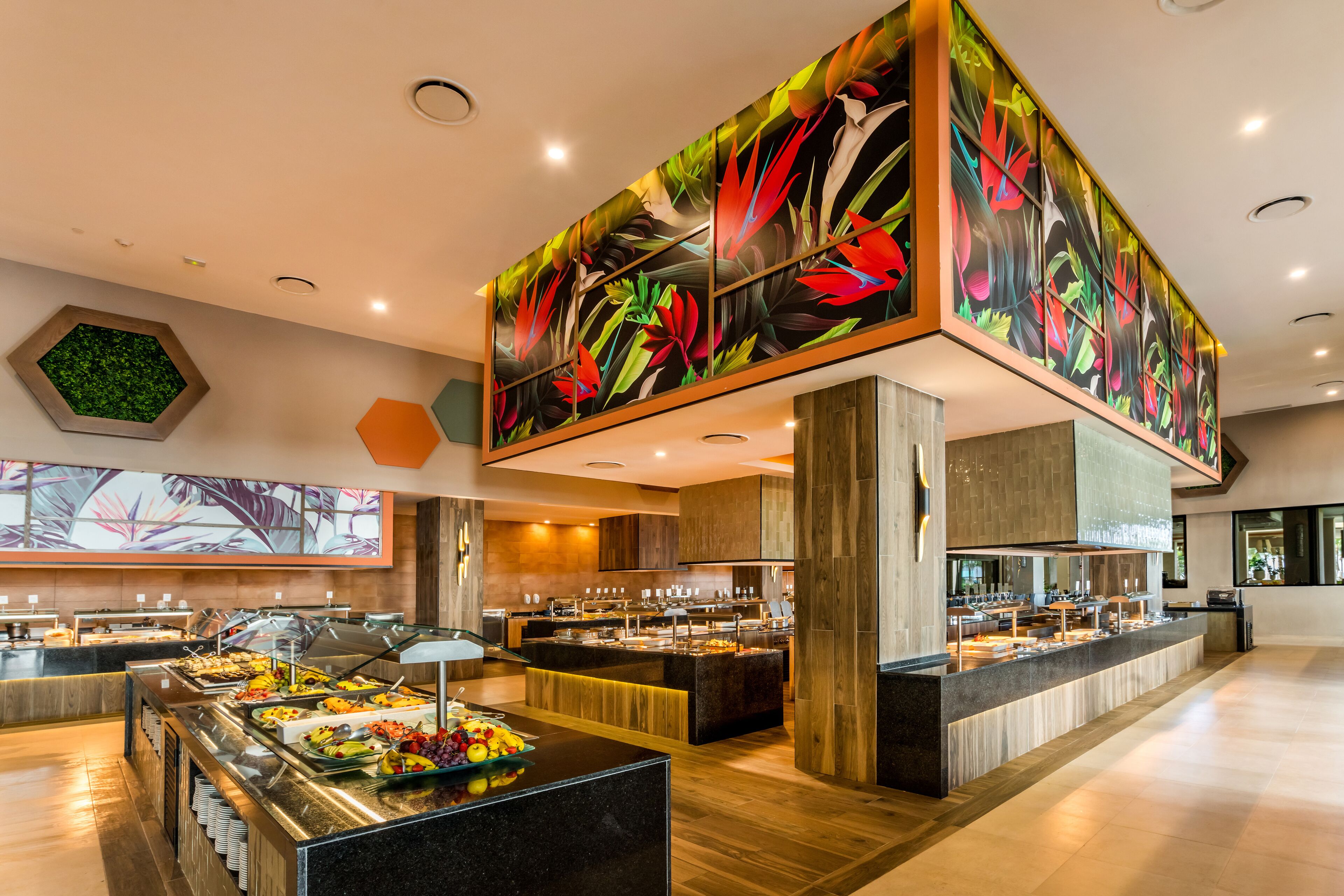 A buffet area with multiple serving stations, a large decorative wall, and a hexagonal green wall art piece.