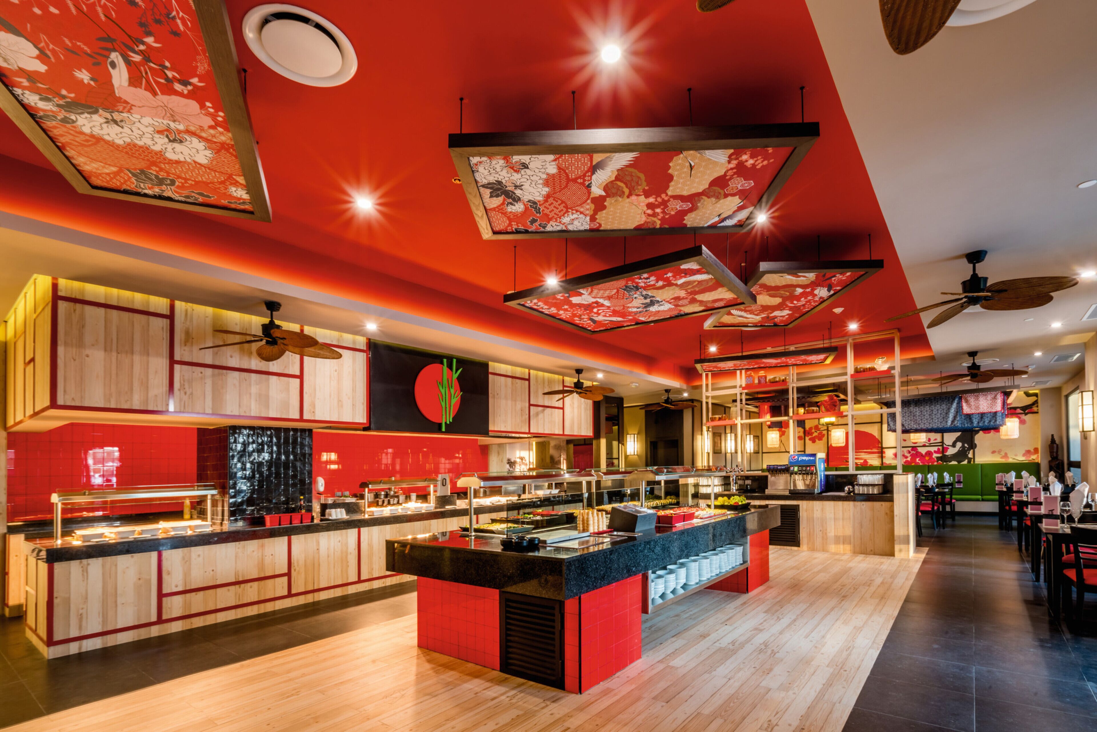 A modern restaurant with a red and black color scheme, wooden flooring, and ceiling fans.
