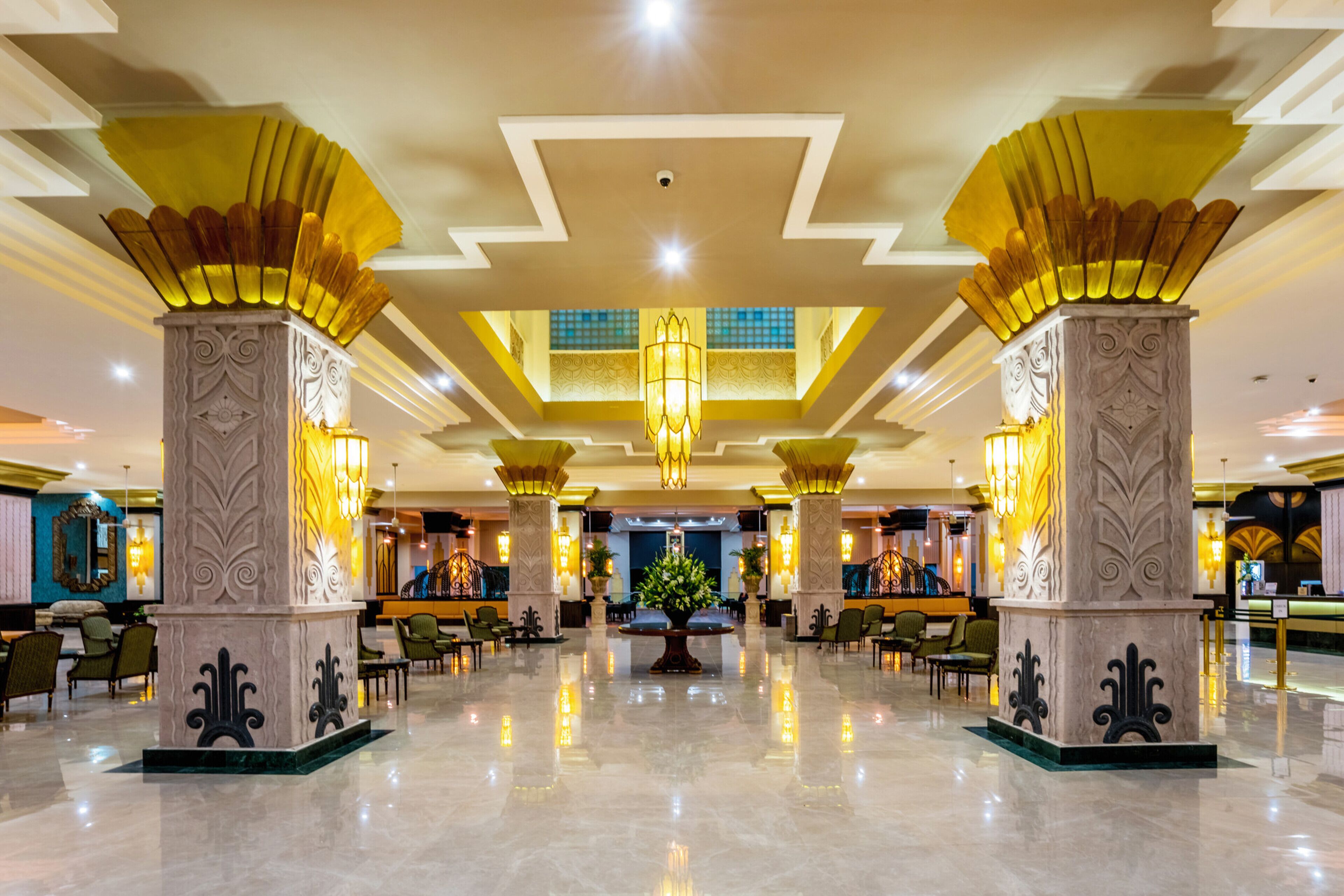 A spacious lobby with high ceilings, ornate columns, and a central floral arrangement.