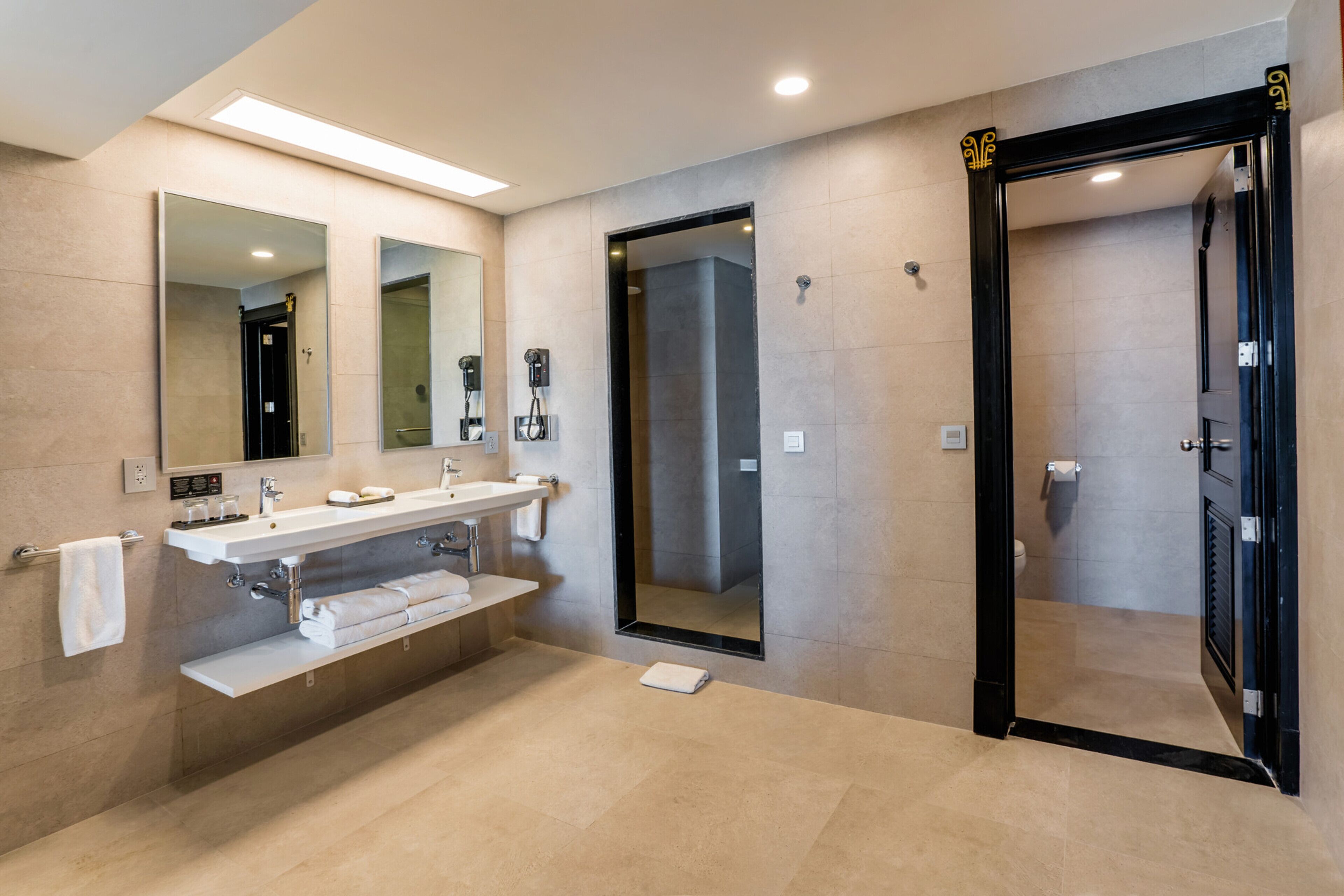 Une salle de bain moderne avec un grand miroir, un lavabo, une douche et des toilettes.