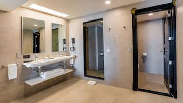 Une salle de bain moderne avec un grand miroir, un lavabo, une douche et des toilettes.
