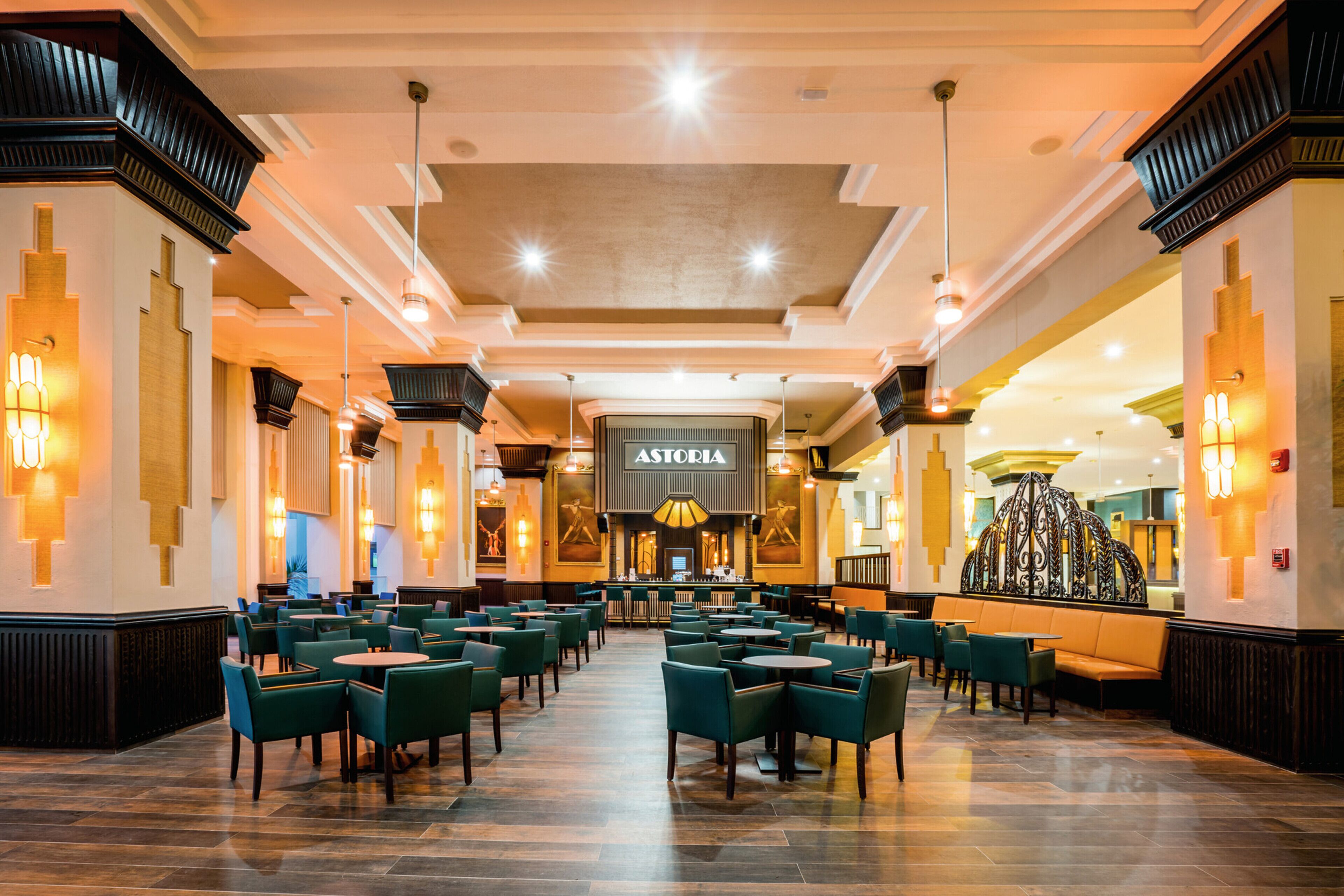 A spacious restaurant with multiple seating areas, including booths and tables, and a central bar area.