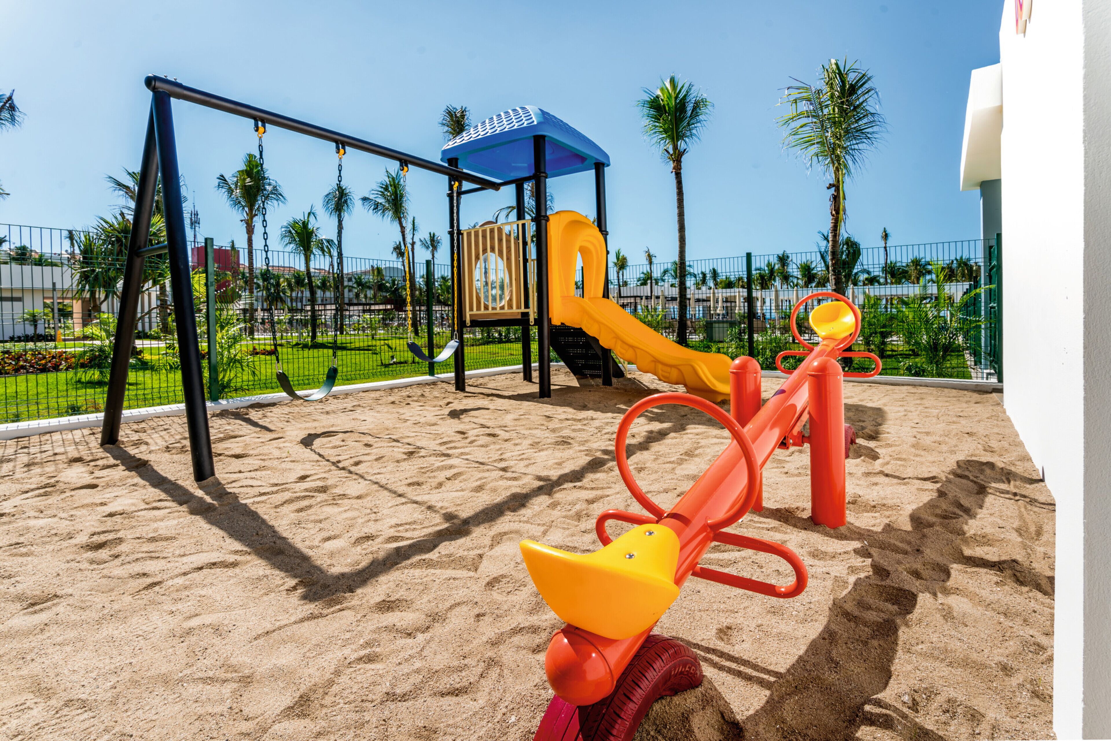 Un parc infantil amb cadira d'oscil·lació, tobogan i estructura per escalar.