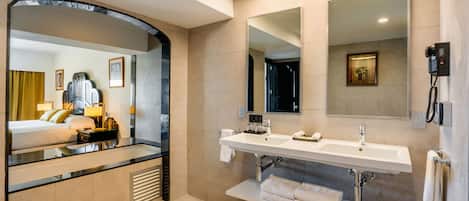A hotel bathroom with a large mirror, two sinks, a towel rack, and a telephone.