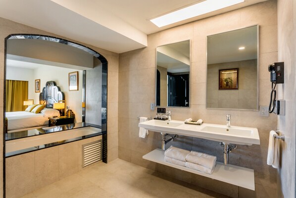 A hotel bathroom with a large mirror, two sinks, a towel rack, and a telephone.