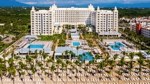 A large resort with multiple swimming pools, palm trees, and a prominent hotel building. - Hotel Riu Vallarta - All Inclusive (Nuevo Nayarit)