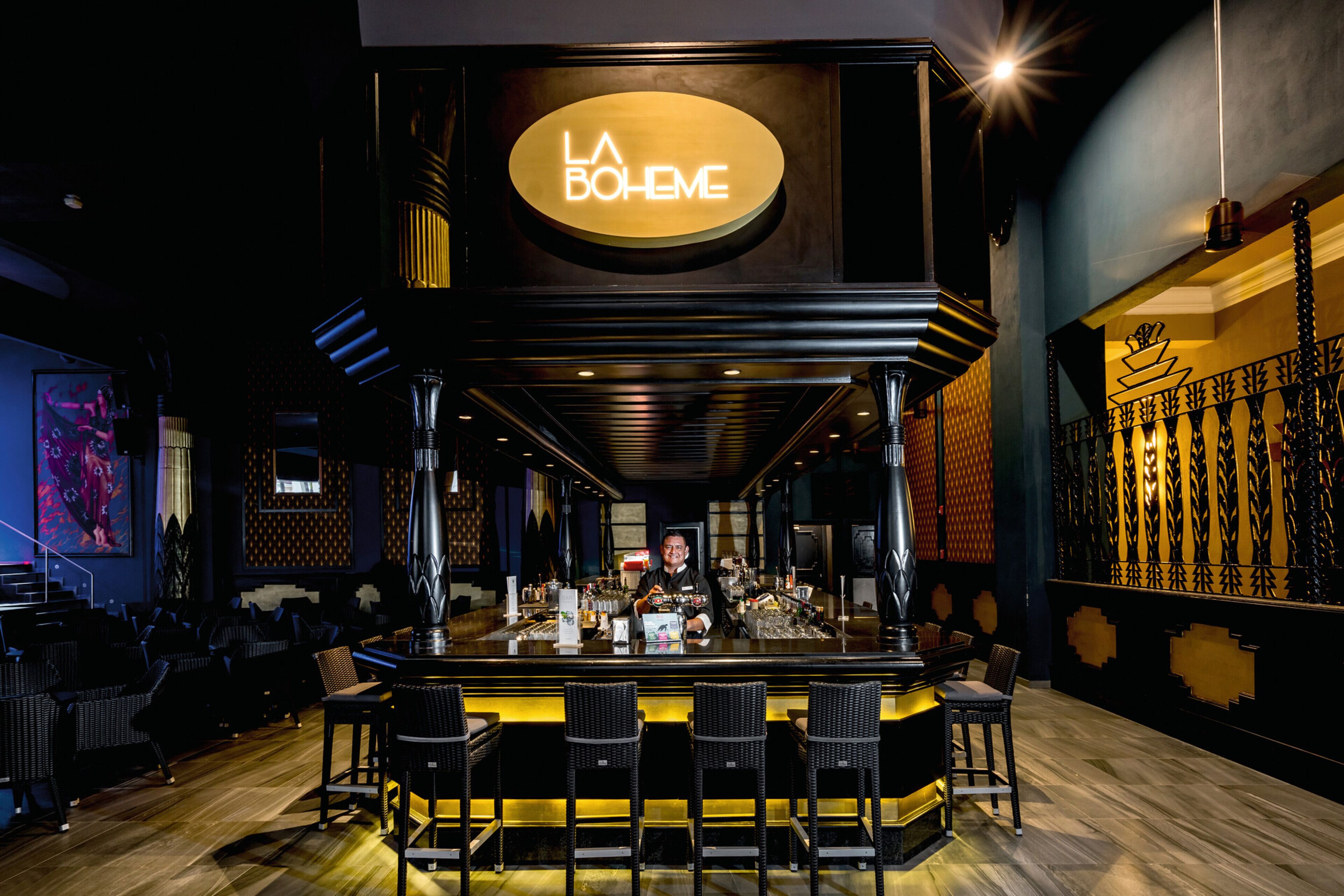 Un espace bar avec un comptoir, des tabourets de bar et un barman.