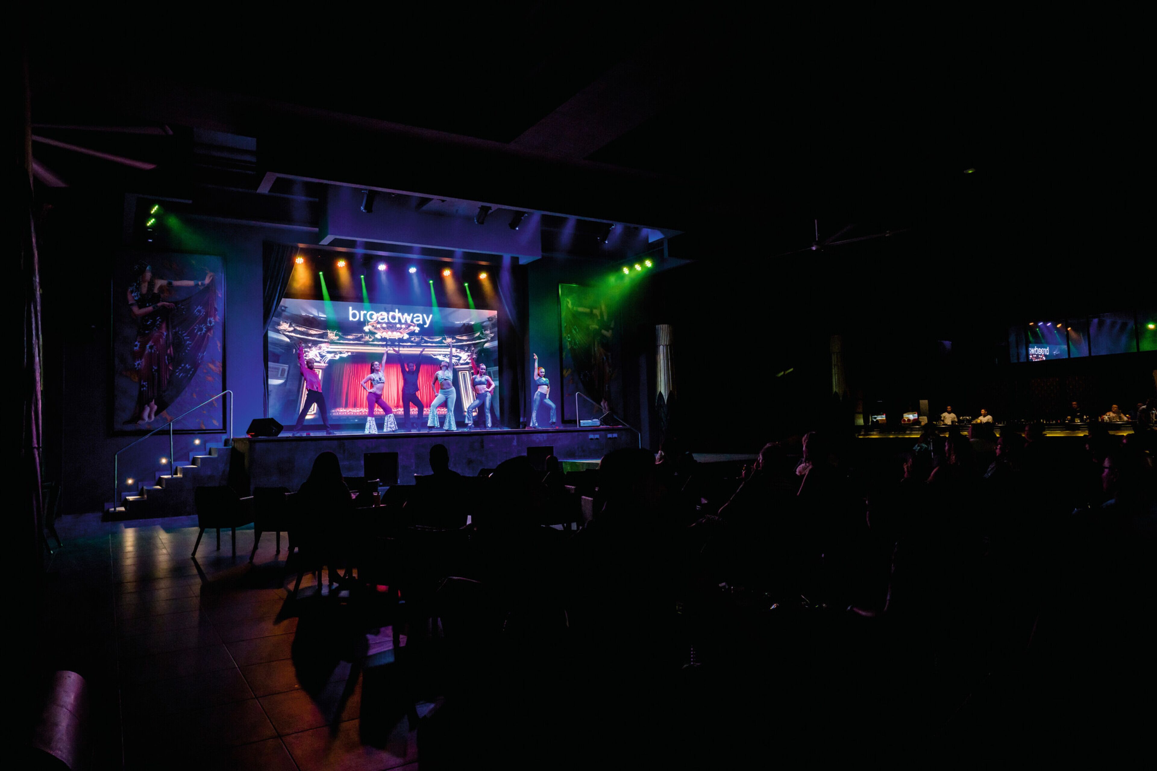 A stage with a 'Broadway' sign, a staircase, and a bar area.