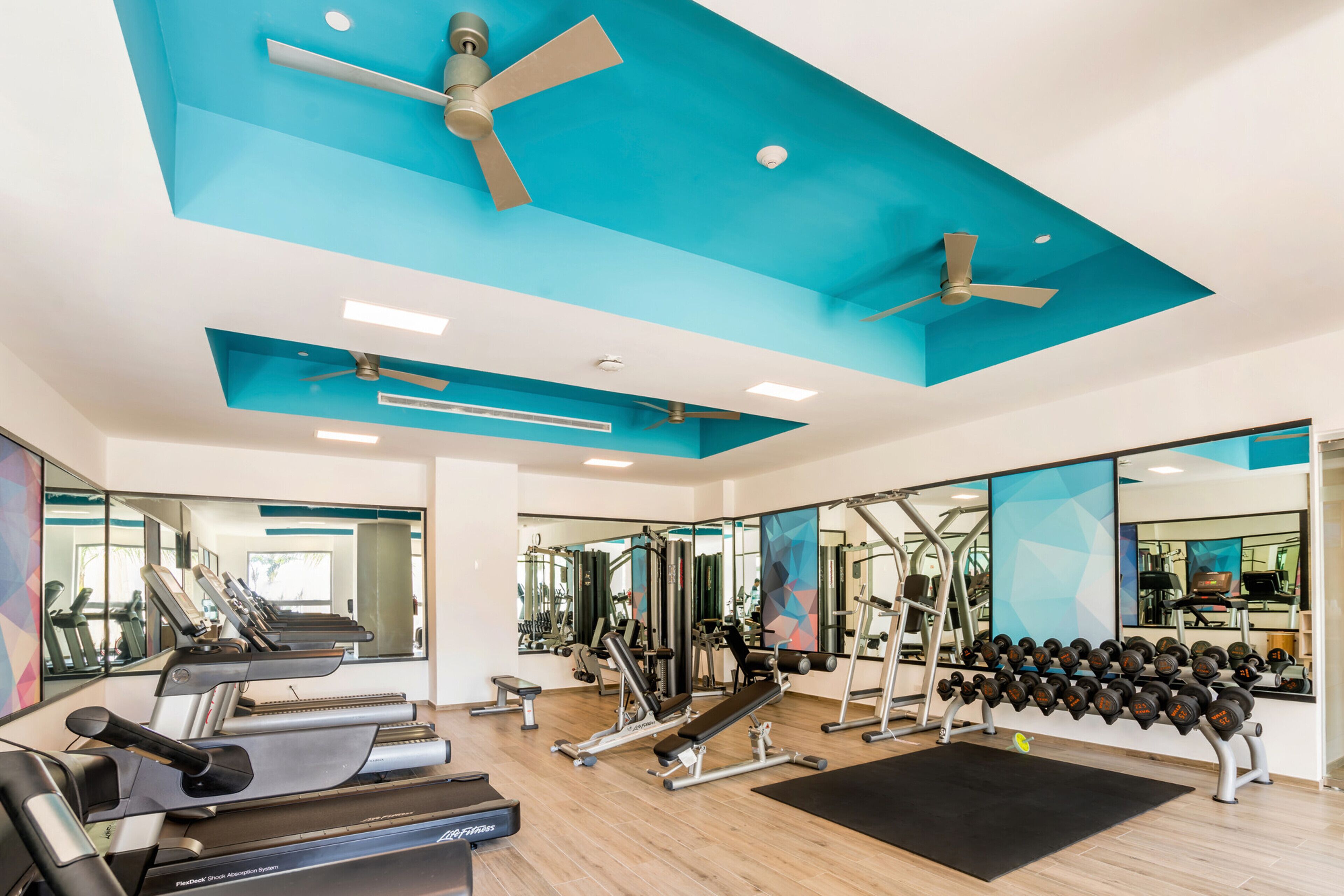 A gym with treadmills, weight machines, and dumbbells.