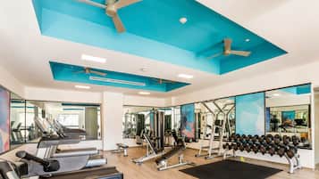 A gym with treadmills, weight machines, and dumbbells.