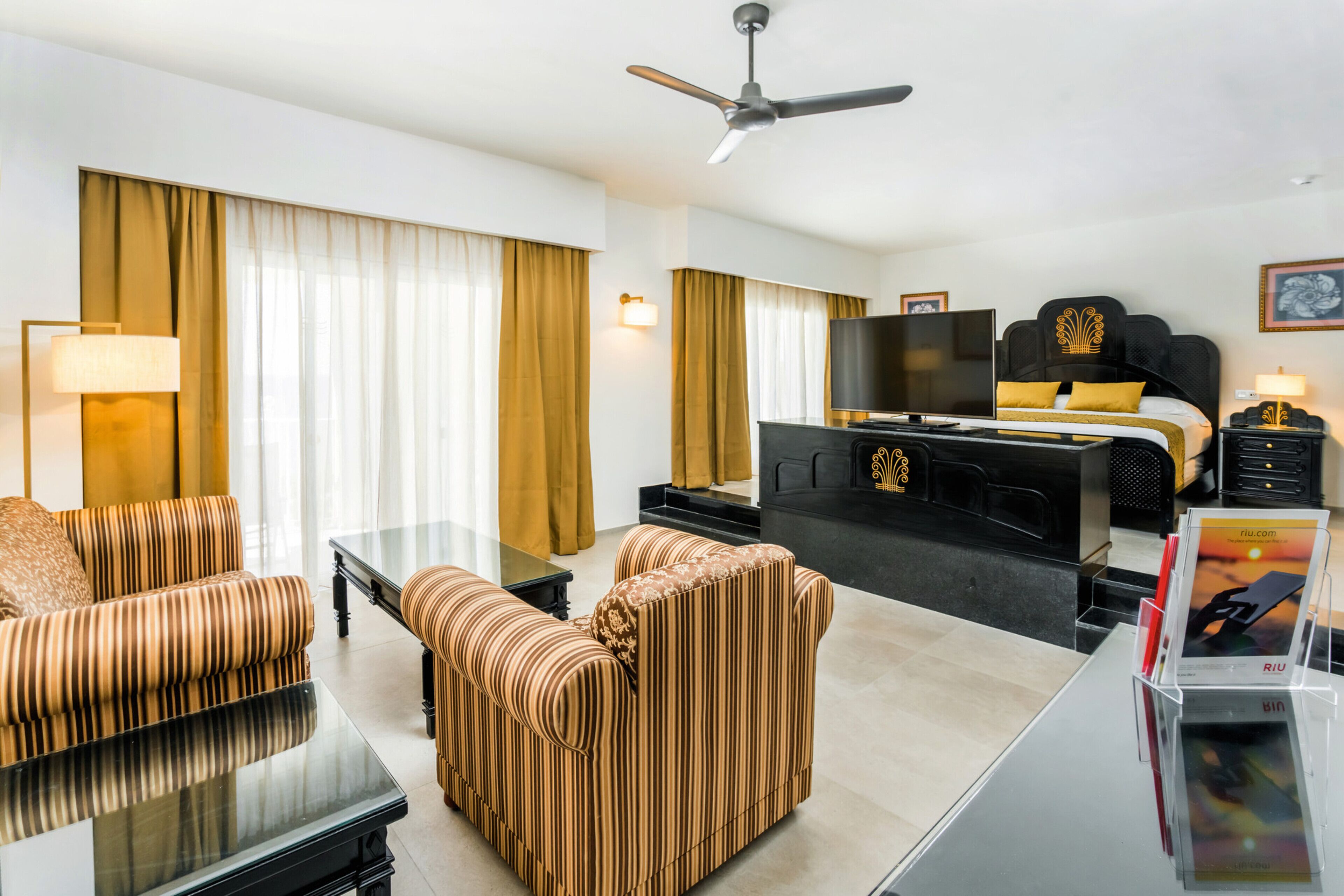 A hotel room with a bed, a TV, a desk, and a sofa.