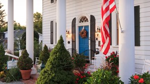 A white house with a blue door, an American flag, and a welcome sign. - Arrowhead Inn (Durham)