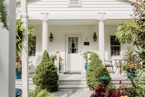 A white house with a porch, columns, and potted plants.