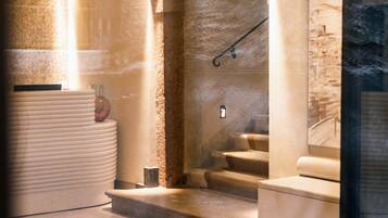 Un área de spa con un mostrador de recepción, una silla de masaje y una escalera que lleva a un nivel superior.