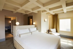 A hotel room with a large bed, a desk, a chair, and a window with curtains.