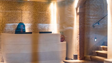 A reception area with a marble reception desk, a stone wall, and a staircase leading to an upper level.