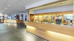 A modern reception area with a wooden counter, a digital kiosk, and a variety of bottled beverages. - Hotel Cabin (Reykjavik)