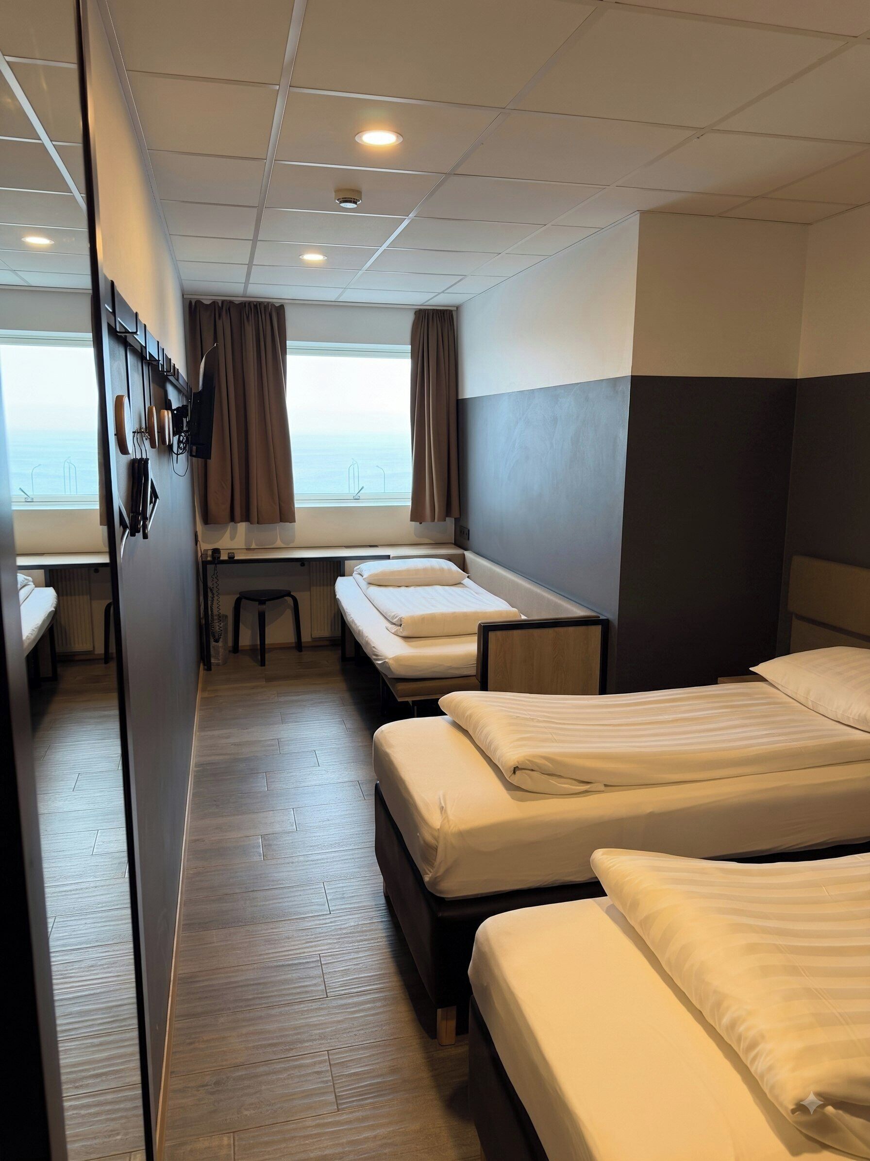 Ein Hotelzimmer mit zwei Betten, einem Schreibtisch und Meerblick.