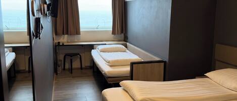 Habitación de hotel con dos camas, un escritorio y vista al mar.