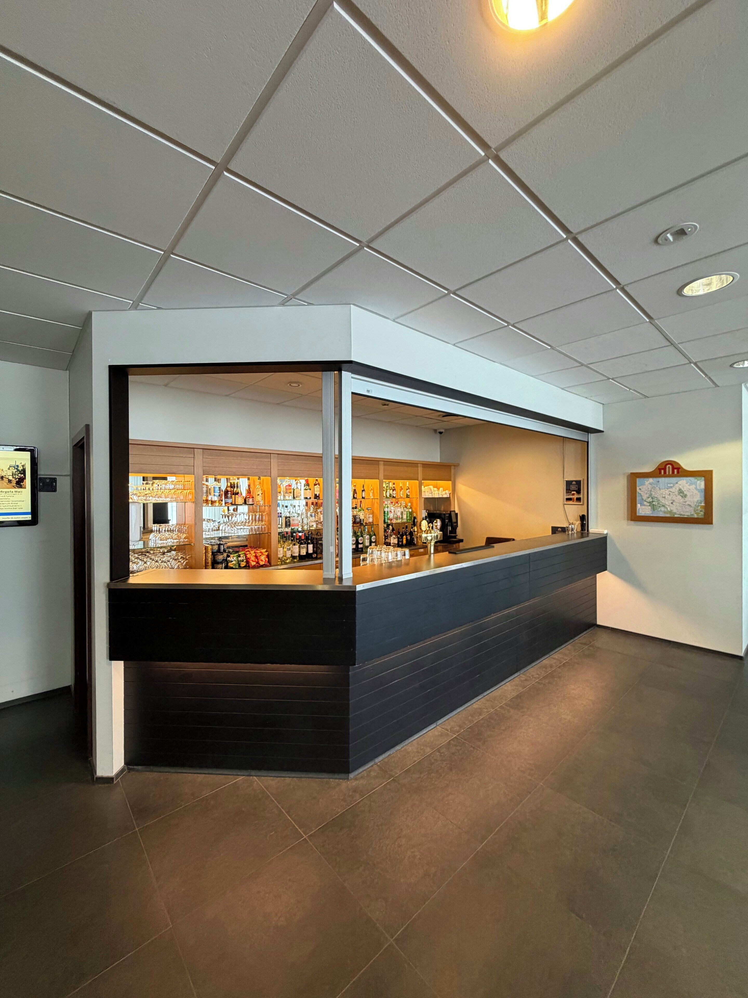A bar area with a counter, shelves of bottles, and a map on the wall.