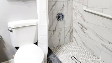 A bathroom with a toilet, shower, and tiled walls.
