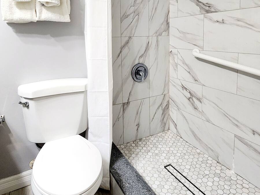 A bathroom with a toilet, shower, and tiled walls.