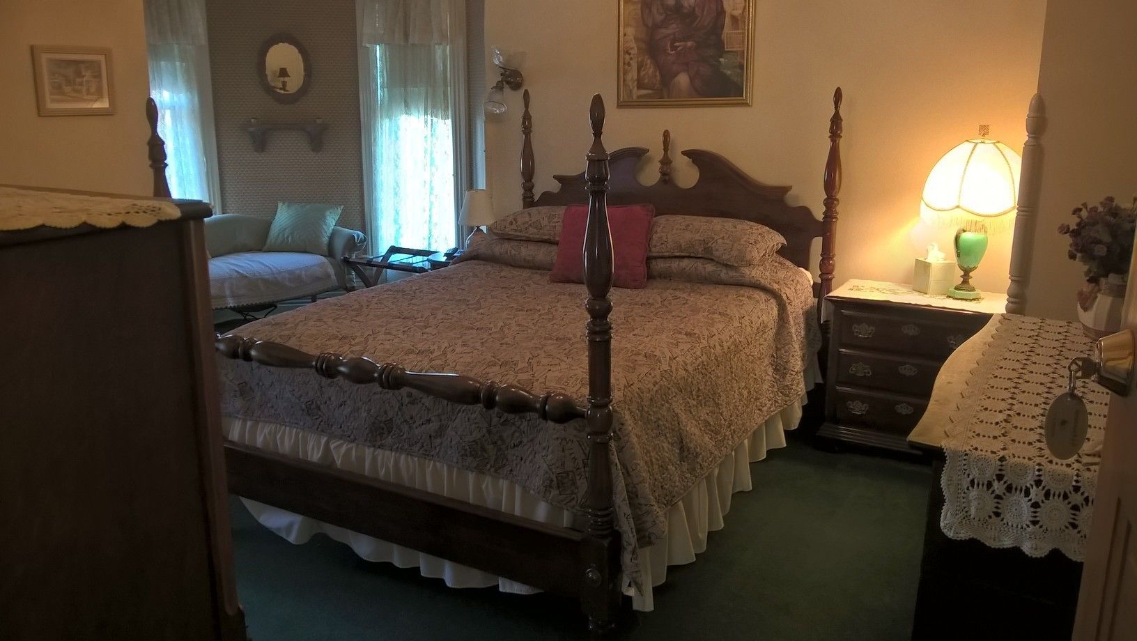 A traditional bedroom with a four-poster bed, a nightstand with a lamp, and a dresser.