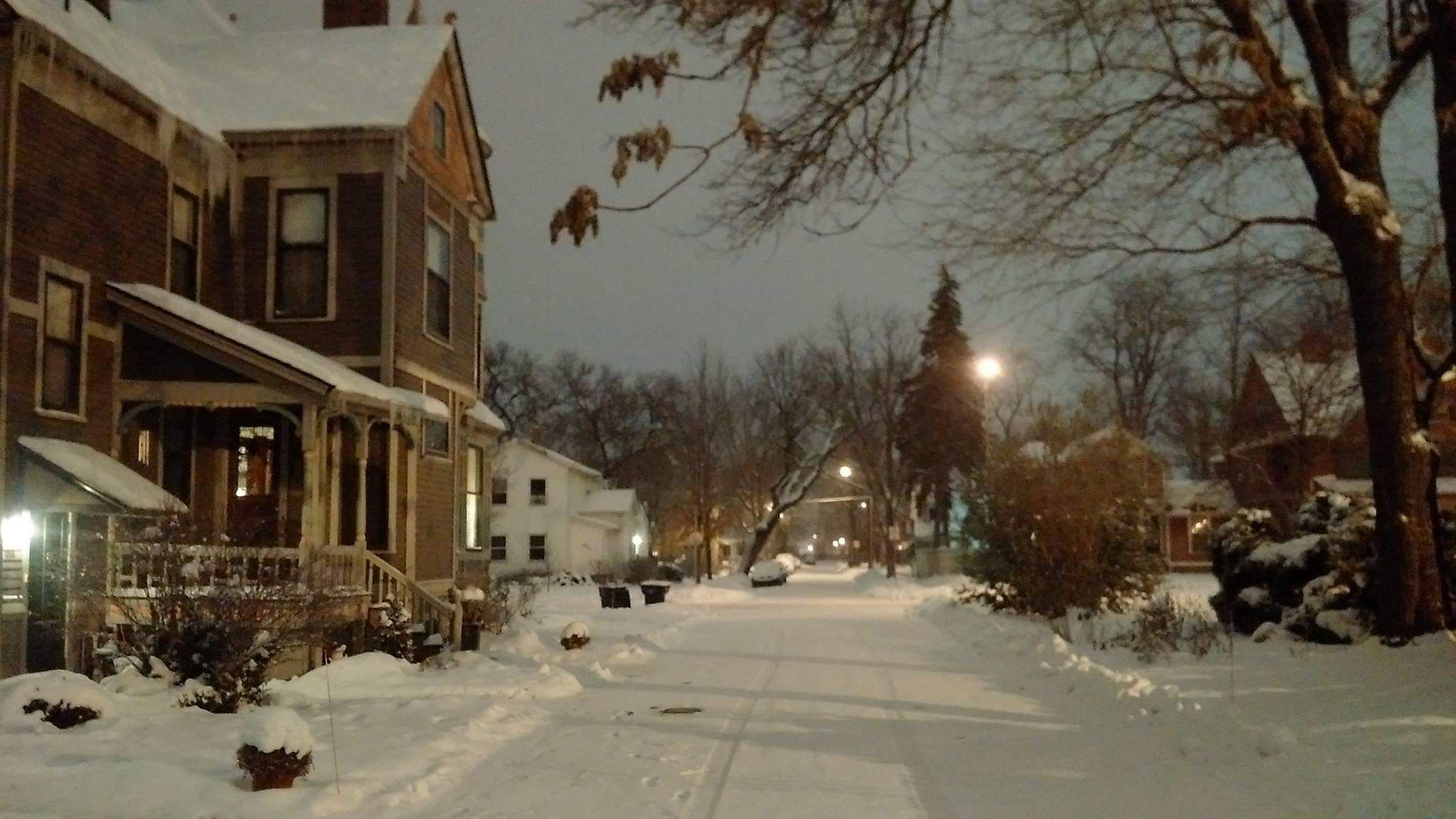A residential street with snow-covered houses and a clear road.