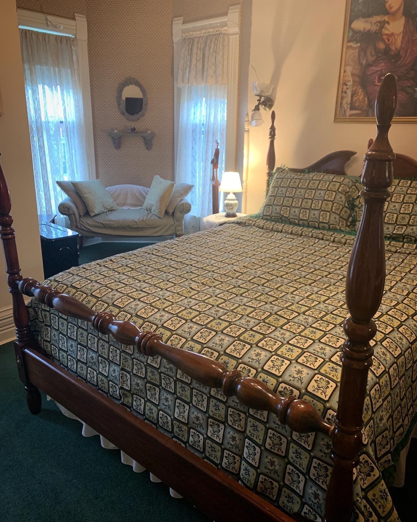 Une chambre à coucher avec un lit à baldaquin, un canapé, un miroir fixé au mur et un tableau.