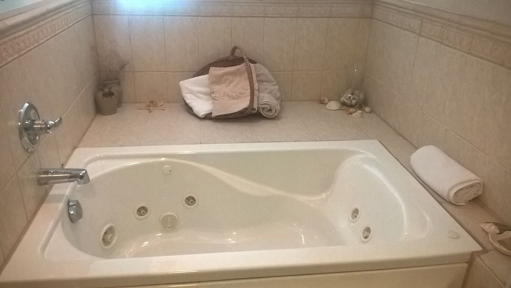A bathroom with a bathtub, a towel, and a small trash bin.