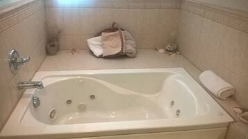 A bathroom with a bathtub, a towel, and a small trash bin.