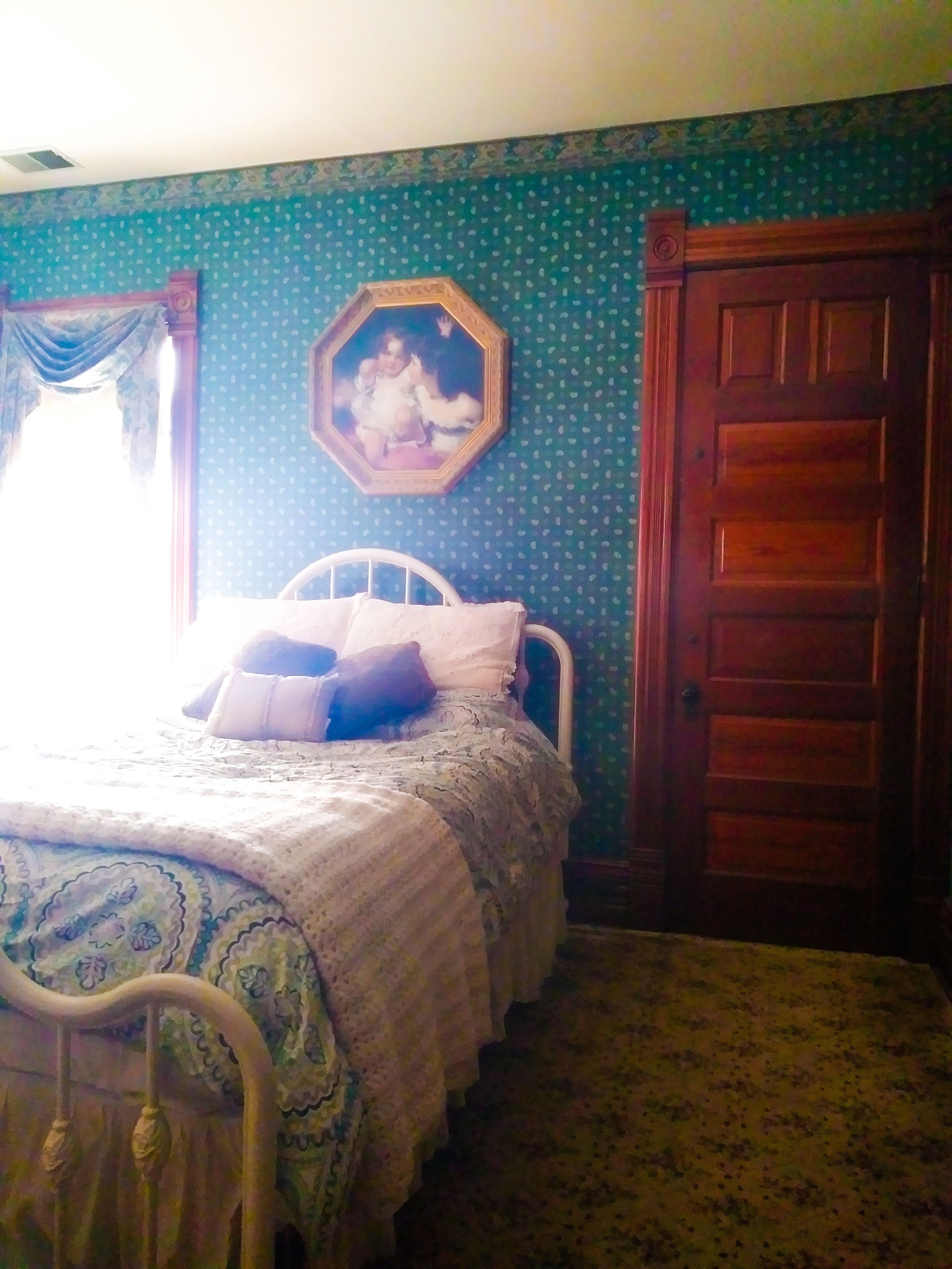 Una camera da letto con un letto, una porta in legno e un muro decorato con un motivo floreale.