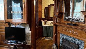 A traditional living room with a wooden cabinet, a fireplace, and a television on a stand.