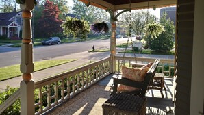 A covered porch with a wicker chair and a hanging planter.