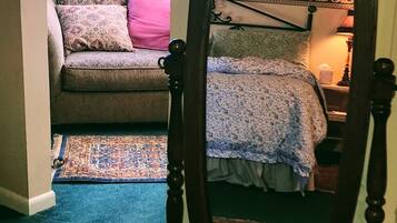 A bedroom with a bed, a nightstand, a lamp, a window, and a patterned rug.